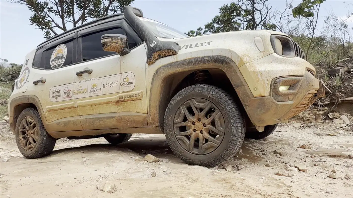 Jeep coberto de barro em trilha de pedra